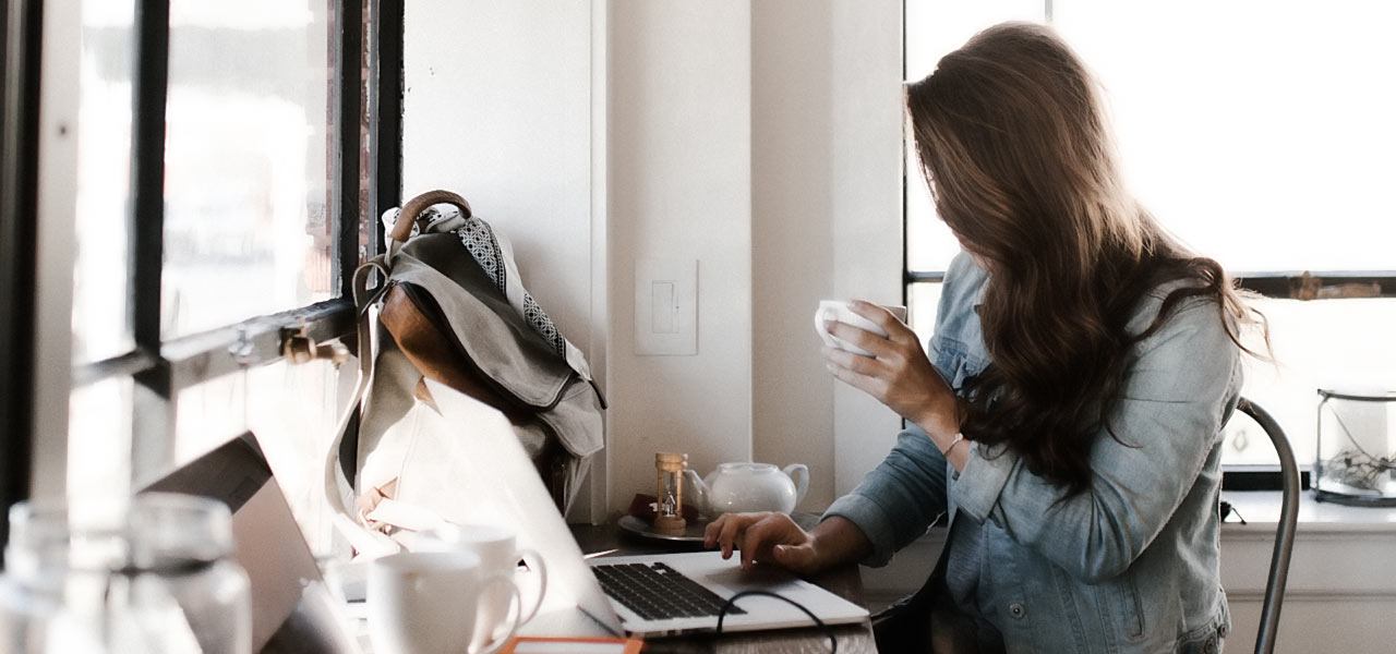 woman drinking coffee while working in home office